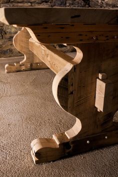 a wooden table sitting on top of a carpeted floor next to a stone wall