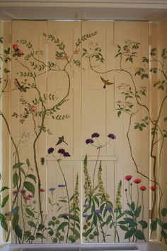 a room with flowers and plants painted on the wall next to a radiator