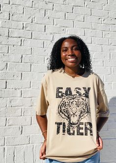 Stay on-trend with the Easy Tiger Oversized Graphic Tee. This tan-colored shirt is designed with a slightly oversized fit, providing both comfort and style. Perfect for any casual occasion, this tee is a must-have for any fashion-forward individual. Spring Oversized Beige T-shirt, Trendy Khaki Crew Neck T-shirt, Oversized Brown T-shirt For Fall, Trendy Brown Relaxed Fit T-shirt, Trendy Beige Relaxed Fit T-shirt, Trendy Beige T-shirt For Streetwear, Trendy Beige Streetwear T-shirt, Casual Beige T-shirt For Day Out, Casual Brown T-shirt With Text Print