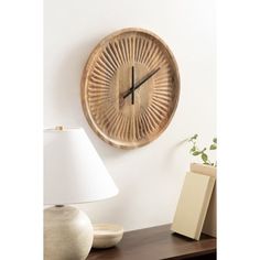 a wooden clock mounted to the side of a wall next to a lamp and vase