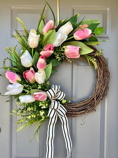 a wreath with pink and white tulips hangs on the front door