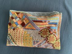 a small pouch is sitting on a blue tablecloth with an orange and yellow pattern