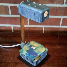 a lamp that is sitting on top of a wooden table next to a brick wall