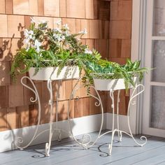 two white planters sitting on top of a wooden floor next to a window sill