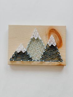 a string art piece with three mountains on it