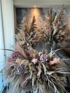 two vases filled with dried flowers next to a wall