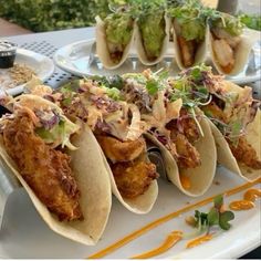 some tacos are sitting on a plate with sauces and garnishes