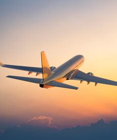 an airplane is flying in the sky at sunset