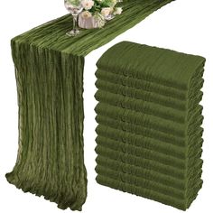 a stack of folded towels sitting next to a vase with flowers on top of it