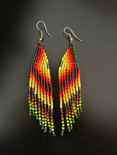 two pairs of colorful beaded earrings on a black surface