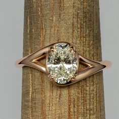 a ring with a diamond in it sitting on top of a piece of wood