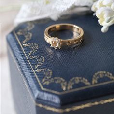 a wedding ring sitting on top of a blue book next to white and yellow flowers