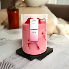 a pink candle sitting on top of a bed