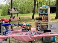 there are many stuffed animals on display at this outdoor event in the woods with pink table cloth