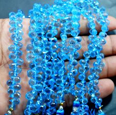 a person holding some blue beads in their hand and the bead is very long