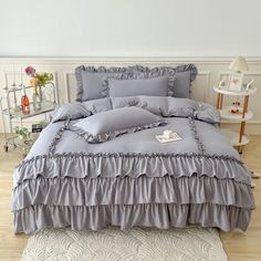 a bed with grey ruffled sheets and pillows