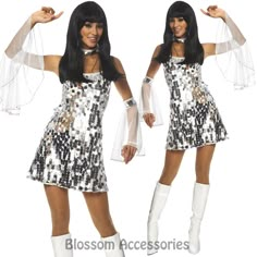 a woman in a sequin dress and white boots posing for the camera with her arms outstretched