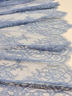 four pieces of blue lace sitting on top of a white tablecloth covered in lacy material