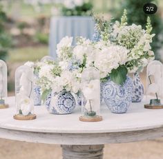 blue and white vases filled with flowers on top of a table