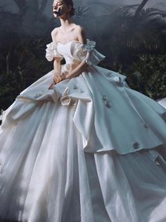 a woman in a white wedding dress with flowers on her head and hands behind her back