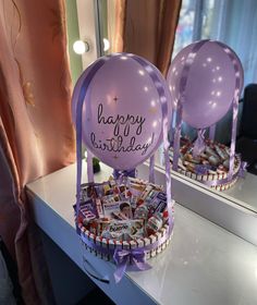 a birthday basket with balloons and candies in it sitting on a table next to a mirror