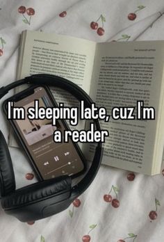 an open book and headphones on top of a bed with the words i'm sleeping late, cuz i'm a reader