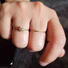 a person's hand with a ring on it and a diamond in the middle