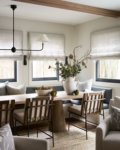 a living room with couches, chairs and a table in front of two windows