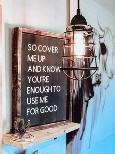 a light hanging from the side of a wall next to a chalkboard with writing on it