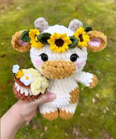 a small stuffed cow with sunflowers on it's head holding an ice cream cone