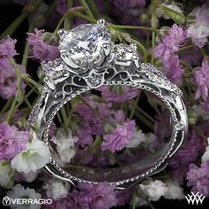 a close up of a wedding ring on top of purple flowers with the words verarago written below it