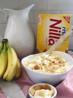 a bowl of yogurt next to two bananas and a carton of milk