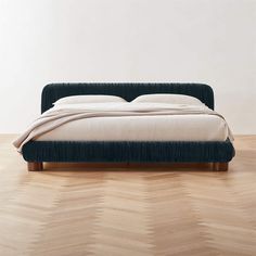 a bed sitting on top of a wooden floor next to a white wall and wood floors