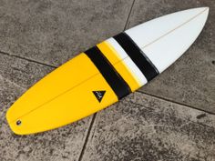 a yellow and white surfboard laying on the ground