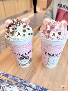 two cups of ice cream with teddy bears on them sitting on a table in a restaurant