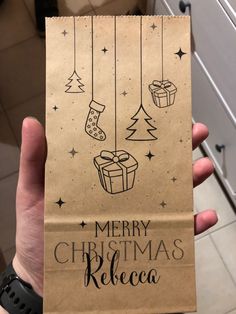 a person holding up a brown paper bag with christmas decorations hanging from it's side