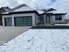 a house with snow on the ground and two cars parked in front of it's garage