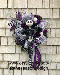 a skeleton wreath is hanging on the side of a building with purple and black ribbons