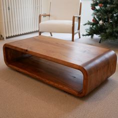 a wooden coffee table sitting on top of a carpeted floor next to a christmas tree