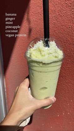 a person holding up a smoothie in front of a red wall with the words banana, mint and pineapple