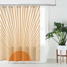 an orange and white shower curtain in a bathroom with potted plants next to it