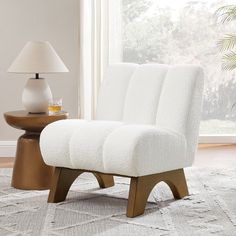 a white chair sitting on top of a rug next to a lamp