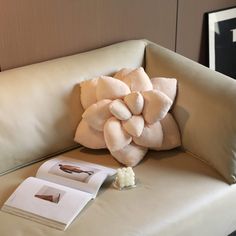 a white couch with a flower on it next to some pictures and a book in front of it