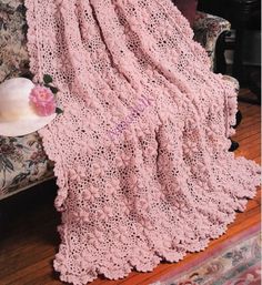 a pink crocheted blanket sitting on top of a couch