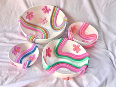 four colorful bowls and two spoons on a white sheet with pink, blue, green, yellow, and purple flowers