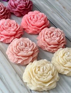 six pink and yellow flowers sitting on top of a wooden table next to each other