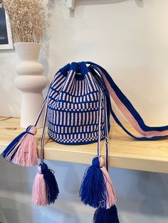 a blue and white bag sitting on top of a wooden shelf next to a vase