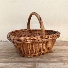 a wicker basket sitting on top of a wooden floor next to a white wall