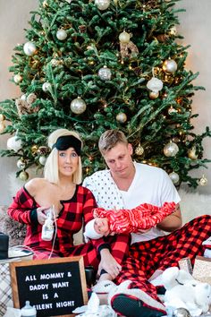 a man and woman sitting in front of a christmas tree