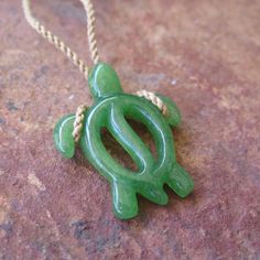 a green turtle shaped pendant on a rope